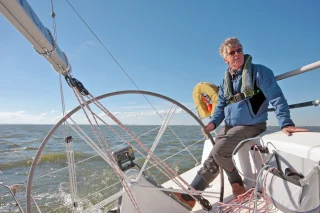 Ein Mann steuert ein Segelboot