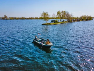 Eine Sloop fährt nahe einer Insel übers Wasser
