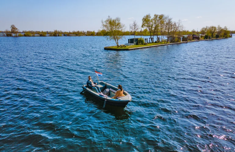 Eine Sloop fährt nahe einer Insel übers Wasser