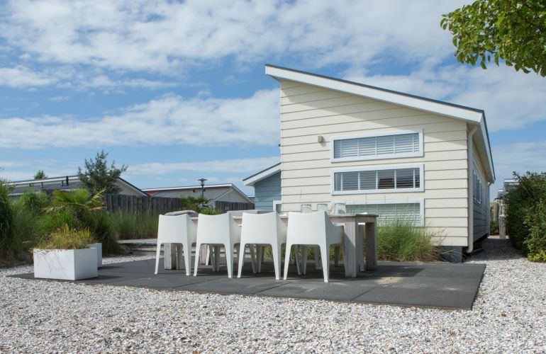 Modern chalet met strak design met buitenterras met kiezelgrond en beplanting