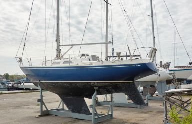Zeilboot op een stalen bok op de kant in de haven voor onderhoud of opslag