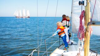 Drie kinderen op een zeilboot op het water